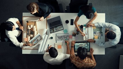 Architect team discussing and pointing and presenting blueprint to interior designer. Aerial view professional business people brainstorming building interior at table with house model. Alimentation.