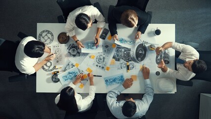 Top down aerial view of smart engineer team working together to design turbine engine. Professional...