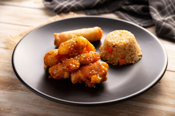 Sweet and sour chicken with fried rice and crispy spring roll, American Chinese food made out of fried, battered chicken covered with sauce. Tasty dish popular in many countries.