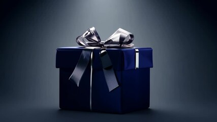 The camera zooms out from a close-up of a dark blue gift box wrapped with a silver ribbon, illuminated by ambient light in a sleek, minimalistic setting.
