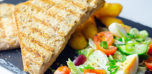A plate of food with a sandwich, cheese sticks, and ketchup