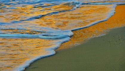 Sea waves and sandy beach in coastline in golden sunset