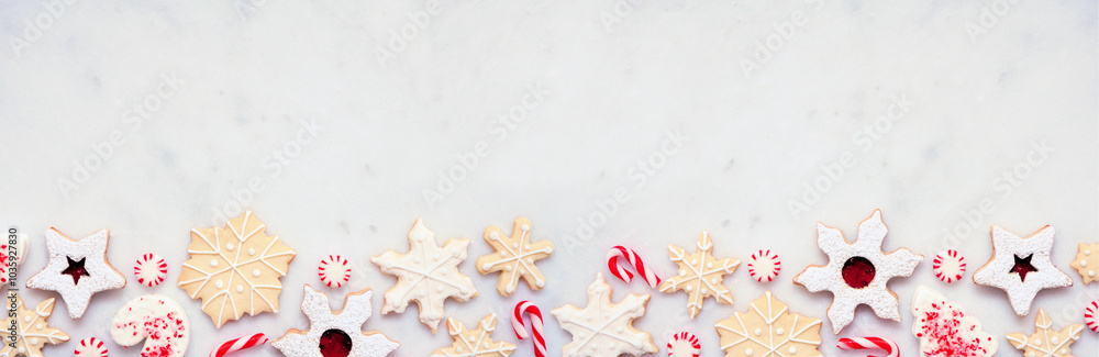 Poster christmas baking bottom border with assorted red and white theme cookies and candies. top view on a 