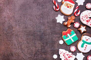 Fun colorful Christmas cookie side border on a dark stone background with copy space. Overhead view. Holiday baking concept.