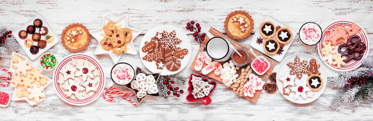 Christmas holiday cookies and desserts table scene. Top view on a white wood banner background. Cookies, tarts, chocolates and hot chocolate tray.