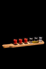 Alcoholic shots on wooden stand with pickle. Alcoholic cocktails. Isolated black background