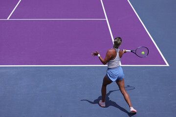 Middle-aged woman performing a backhand shot in a tennis competition.