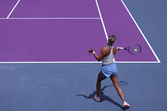 Middle-aged woman performing a backhand shot in a tennis competition.