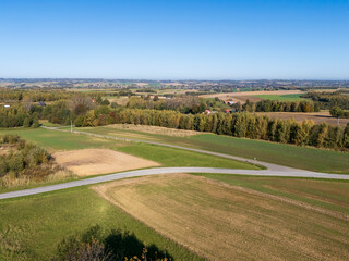 Aerial view of lush green fields and agricultural land under a clear blue sky. Ideal for nature and landscape themes.