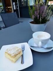 Kawa latte i ciasto na stoliku w restauracji na zewnątrz.