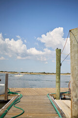 Wooden pier on water with blue sky and billowing clouds.