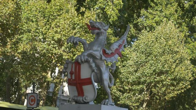 A panning shot of the statue of England&rsquo;s dragon boundary mark in a park.