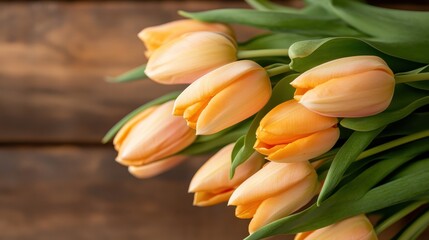 Obraz premium An elegant display of orange tulips, with soft petals and green leaves, artistically arranged against a wooden backdrop, embodying natural beauty and tranquility.