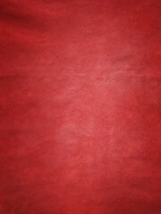 Red suede background with light in the center. Vertical red texture macro.