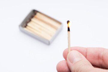 Hand holding burning match stick on white background