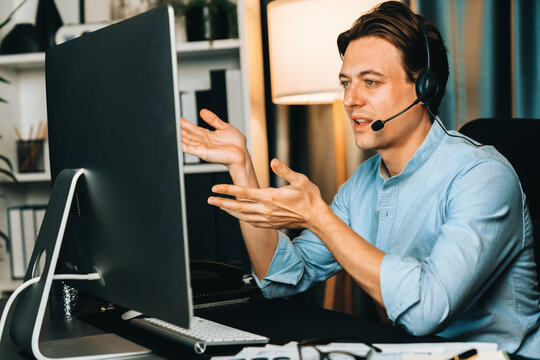Call center consulting with customers on headphones on monitor in business paragraph with typing on pc with dynamic data marketing analysis planning at modern home office at night time. Pecuniary.