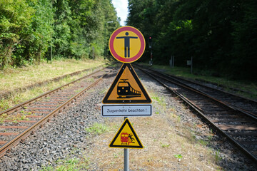 Warnschilder an Übergang für Reisende über Gleis an Bahnhof - Stockfoto