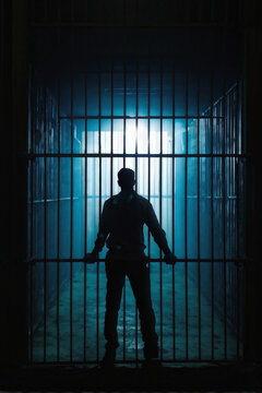 A dramatic silhouette of a man behind prison bars, lit by mysterious blue light. The image evokes a powerful sense of confinement and isolation. Generative A