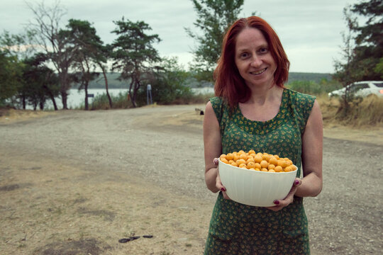 Bowl of yellow berries alycha in hands of a young smiling woman