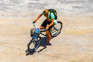 Long haired man rides away on a bicycle in Mexico.