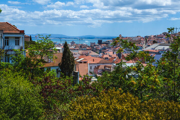 Obraz premium a scenic view overlooking a cityscape with red-tiled rooftops and traditional architecture, extending toward a large body of water in the background