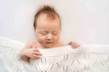 Peaceful sleeping baby wrapped in cozy knit blanket on white background