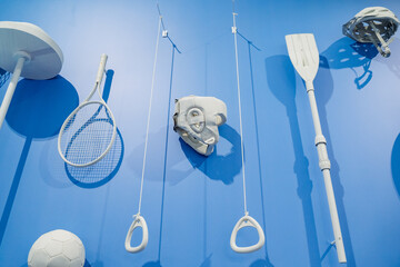There is a striking blue wall adorned with various white objects that are hanging from it in an...