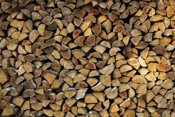Stacked chopped wood logs in woodpile. Preparation of firewood for the winter. Pile of wood logs in village. Wooden stumps. Alternative Fuel for heat in the house. Industrial concept