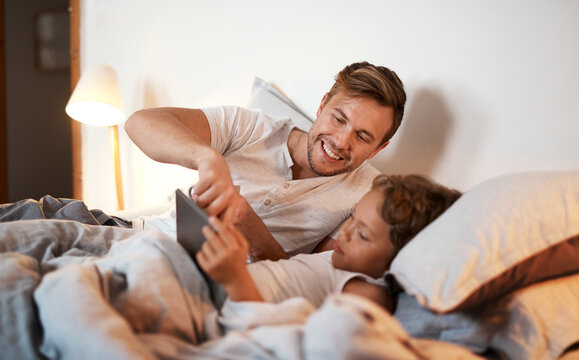 Bedtime, ebook on tablet and father with son in home at night for bonding, education or reading. App, social media or storytelling with family of single parent man and boy child in bedroom together