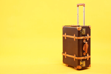 One new brown suitcase on yellow background, space for text