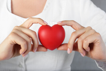 Obraz premium Doctor holding red heart on grey background, closeup