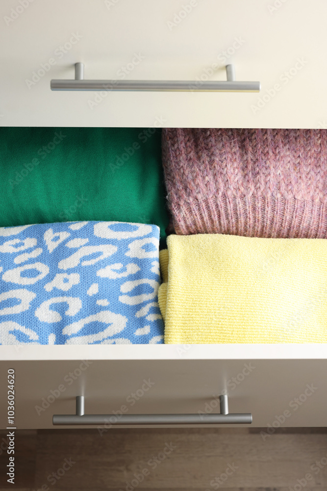 Poster Chest of drawers with different folded clothes, above view