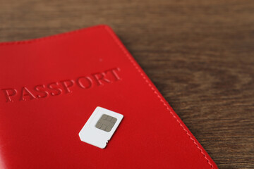 Passport and SIM card on wooden table, closeup