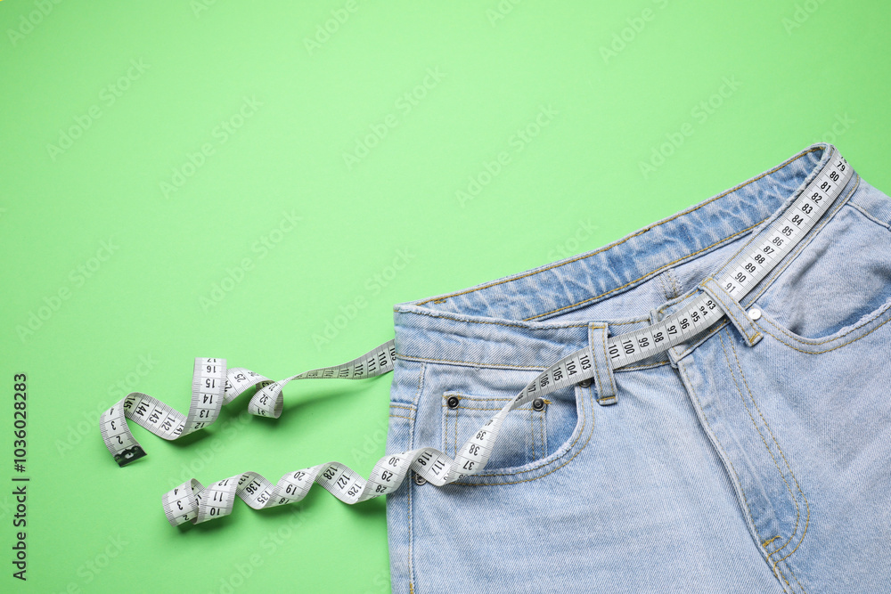 Poster Jeans and measuring tape on green background, top view