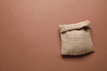 One burlap sack on brown background, top view. Space for text
