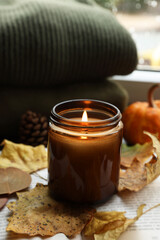 Burning candle and dry leaves on open book. Autumn atmosphere