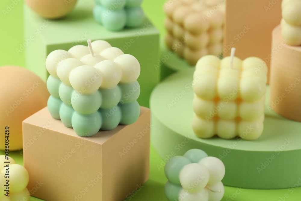 Sticker Beautiful bubble candles and geometric figures on green background, closeup