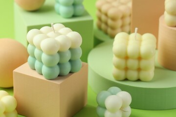 Beautiful bubble candles and geometric figures on green background, closeup