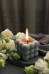 Burning bubble candle and beautiful flowers on grey wooden table, closeup