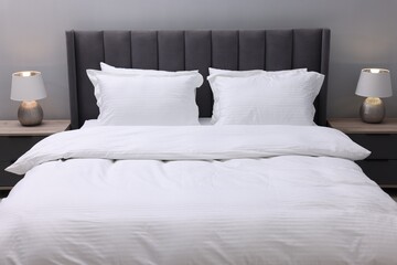 Bed with clean linens and pillows indoors