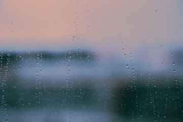 The window glass is coated in a thin film of water from the recent rainfall. A hazy image of the surrounding landscape can be seen through it, creating a beautiful backdrop.