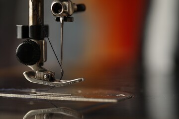 Sewing machine with thread on blurred background, macro view. Space for text