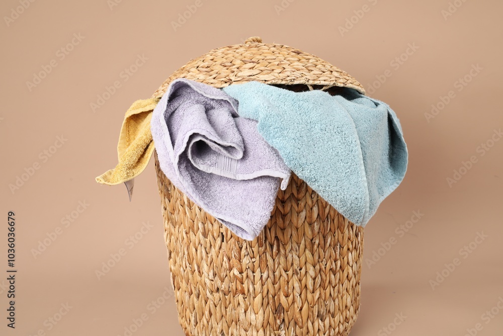 Poster Wicker basket full of laundry on beige background