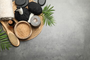 Spa composition with herbal bags and burning candle on grey table, flat lay. Space for text