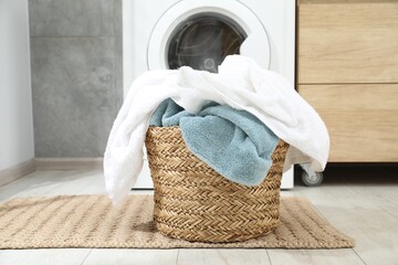 Wicker basket full of laundry on floor in bathroom