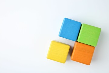 Many wooden colorful cubes on white background, top view. Space for text