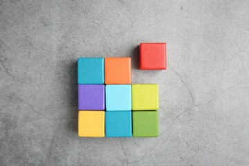 Many wooden colorful cubes on gray textured background, top view