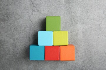 Pyramid of colorful cubes on gray textured background, top view