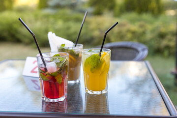 Three drinks on a table with straws in them
