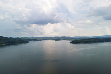 A scenic view of a tranquil lake reflecting the sky, surrounded by lush green hills. Perfect for nature lovers and landscape photography enthusiasts.